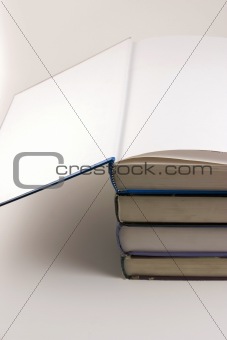 Books stacked up with the cover open on the top