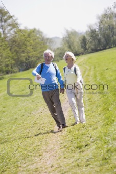 Couple walking on path in park holding hands and smiling