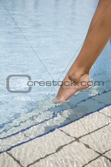 Feet step into the swimming pool
