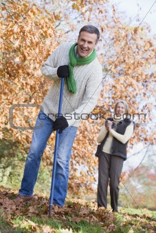 Senior couple tidying autumn leaves