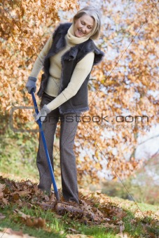 Senior woman tidying autumn leaves