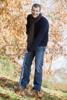 Young man clearing autumn leaves