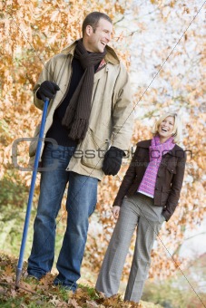 Couple raking up autumn leaves