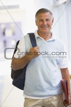 A man with a backpack standing in a campus corridor