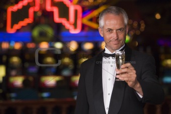 Man in tuxedo drinking champagne in casino