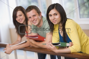 Three college students leaning on banister