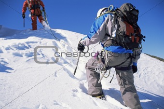 Young men mountain climbing on snowy peak