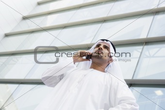 A Middle Eastern businessman talking on the phone outside an off