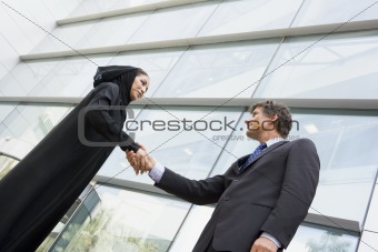 A Middle Eastern businesswoman and a Caucasian man shaking hands