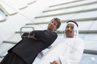 A Middle Eastern businessman and a Caucasian businessman smiling