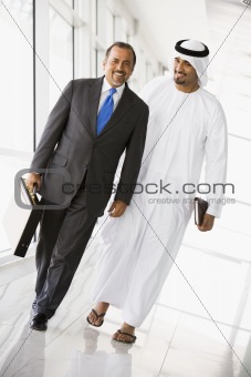 Two Middle Eastern businessmen walking down a corridor