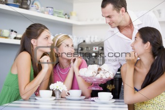 A cafe waiter offers young women teacakes
