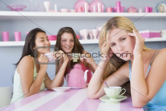 Two young women enjoying a tea party while one sits apart