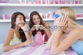 Two young women enjoying a tea party while one sits apart wearin
