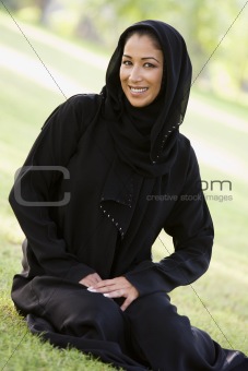 A Middle Eastern woman sitting in a park