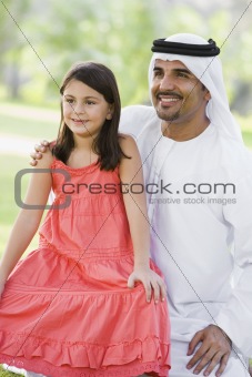 A Middle Eastern man and his daughter sitting in a park