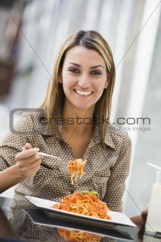 Woman eating pasta at cafe