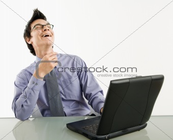 Laughing businessman on laptop.