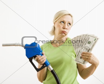Unhappy woman with gas pump and money.