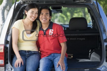 Couple sitting in back of van smiling