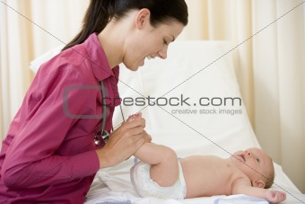 Doctor giving checkup to baby in exam room smiling