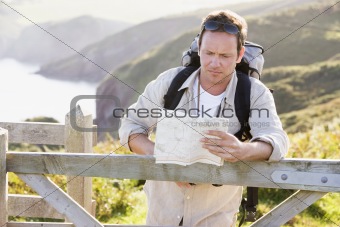 Man relaxing on cliffside path holding map