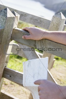 Man's hands on fence holding map