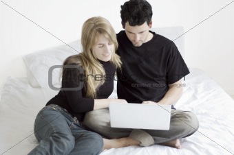 Couple Relaxing with Laptop in Bed