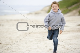 Young boy running on beach smiling