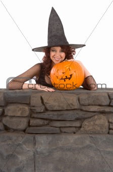 Teen girl in Halloween hat with carved pumpkin