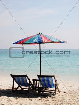 Deck chairs on a white sandy beach 