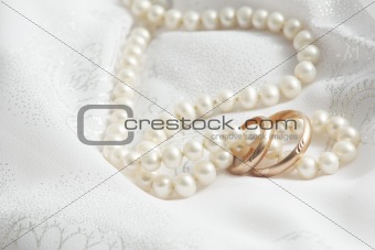 Wedding background: pearls and wedding bangs on a fabric.