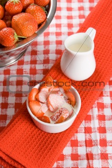 Sliced strawberries with cream in a white pot