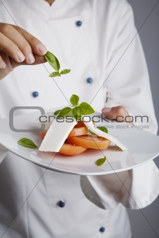 chef adding greens to dish