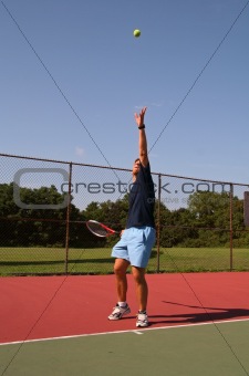 Young man serving tennis ball