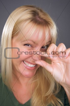 Woman Indicating A Little Bit with Her Hand Against a Grey Background.