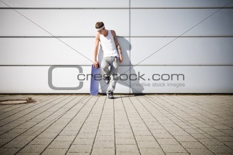 skater holding his skateboard while taking a break