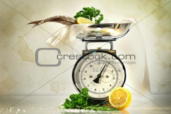 Weight scale with fish and lemons against a grungy, antique back