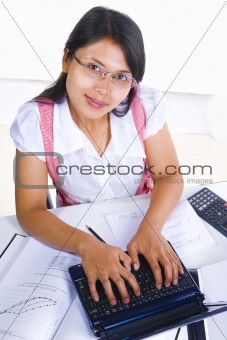 Female scholar typing while looking at camera