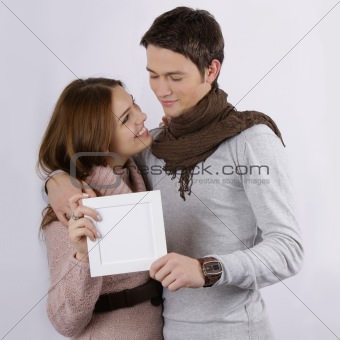 young attractive couple hugging and holding blank sign