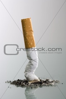Cigarett butt end crushed into ashtray - grey background