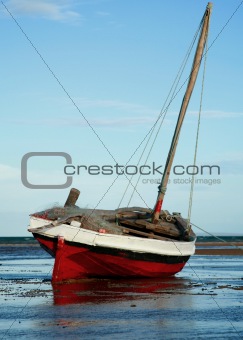 Red and White Sailing boat stranded at low tide in ocean Mozambi