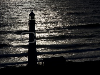 Lighthouse Silhouetted Against Ocean at Dusk