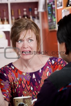 Appalled woman in coffee house with male friend