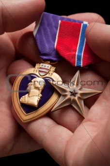 Man Holding Purple Heart and Bronze War Medals in The Palm of His Hand.