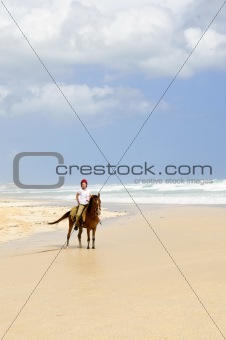 Girl riding horse on beach