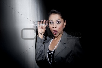 Pretty young Hispanic woman using glass to eavesdrop