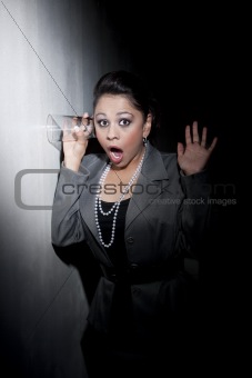 Pretty young Hispanic woman using glass to eavesdrop