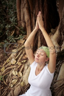 Woman in white meditating in front of Bodhi Tree Roots