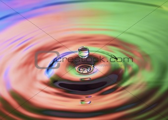 Colorful water drop falling into water